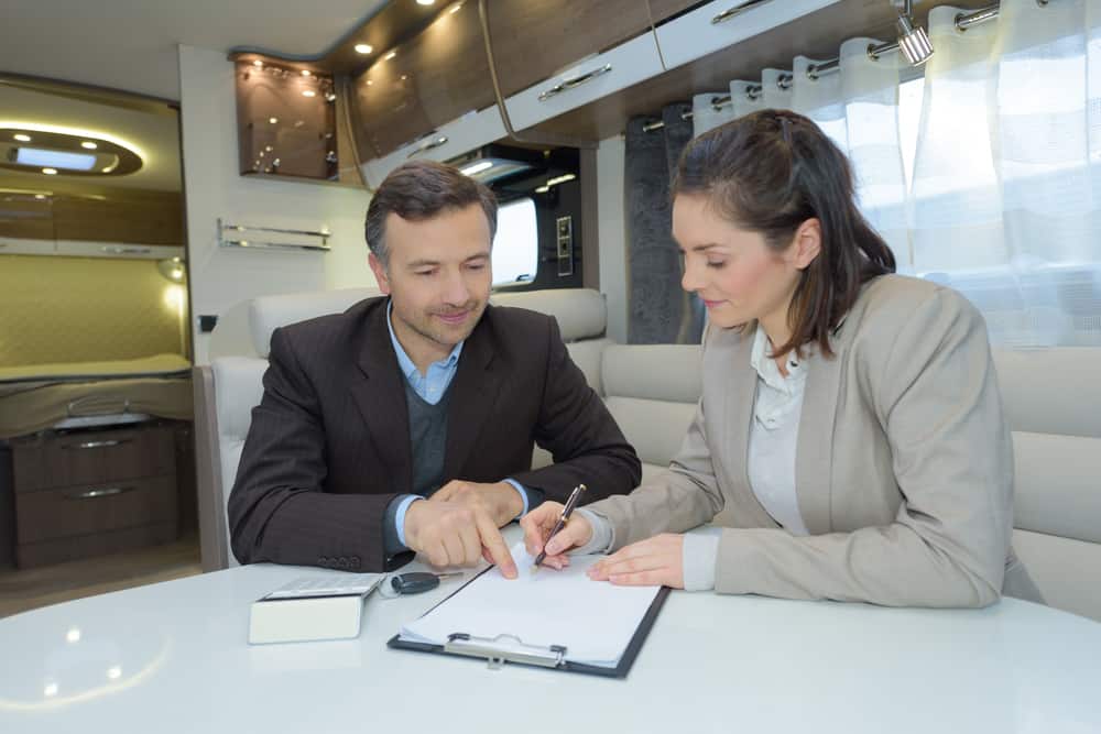 woman buying a used camper at the best time of year and signing a contract