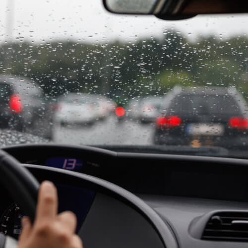 front view of traffic in rain from the inside drivers seat of a car