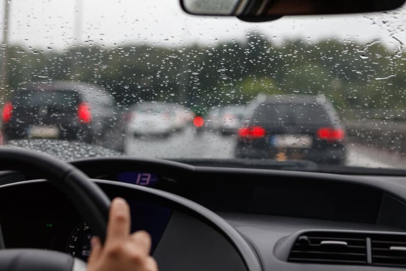 front view of traffic in rain from the inside drivers seat of a car