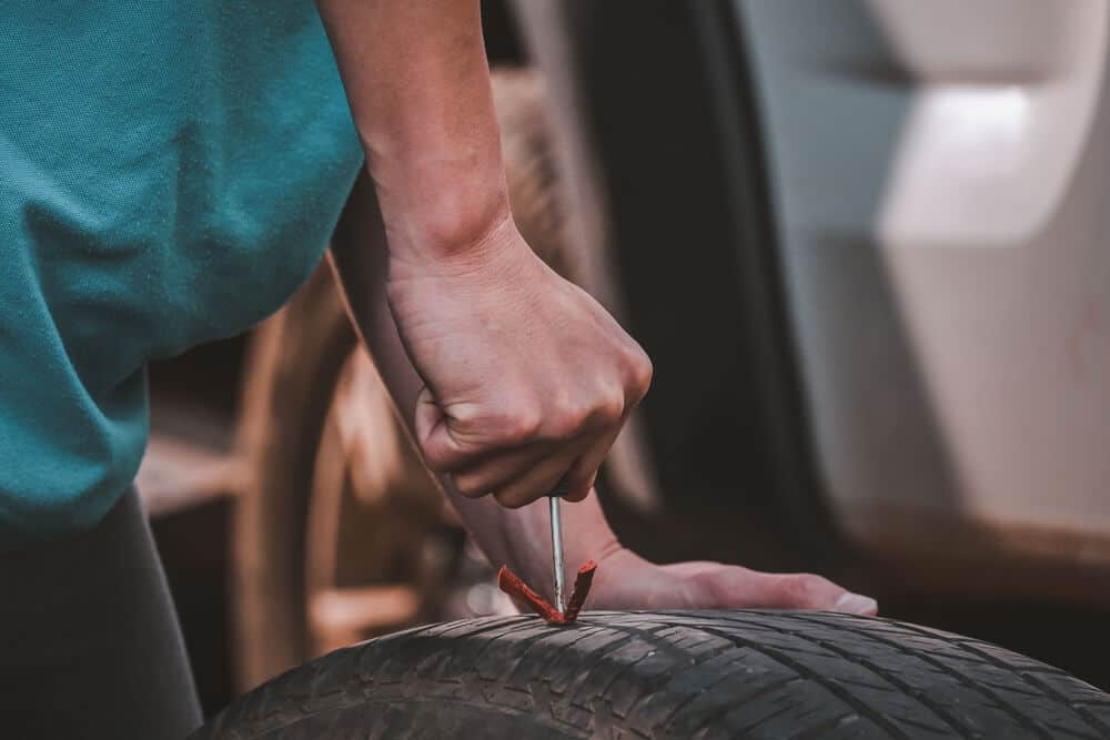 hand patching up and fixing a flat tire with plug