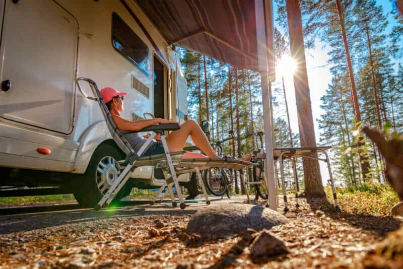 side view of woman in front of her camper in the woods