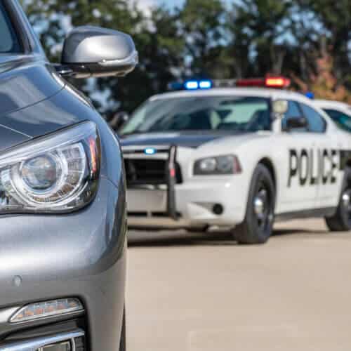 Two police vehicles stop a sedan on a routine traffic stop