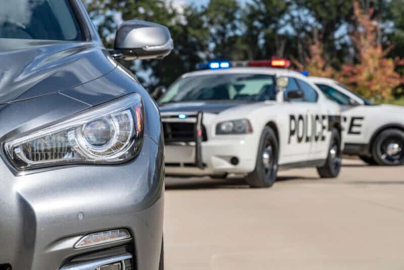 Two police vehicles stop a sedan on a routine traffic stop