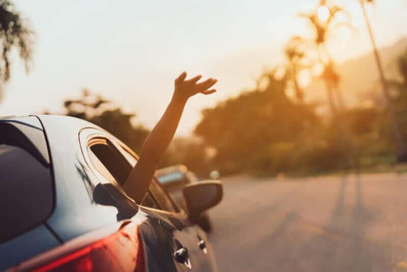 hand happily coming out or moving car window during a roadtrip