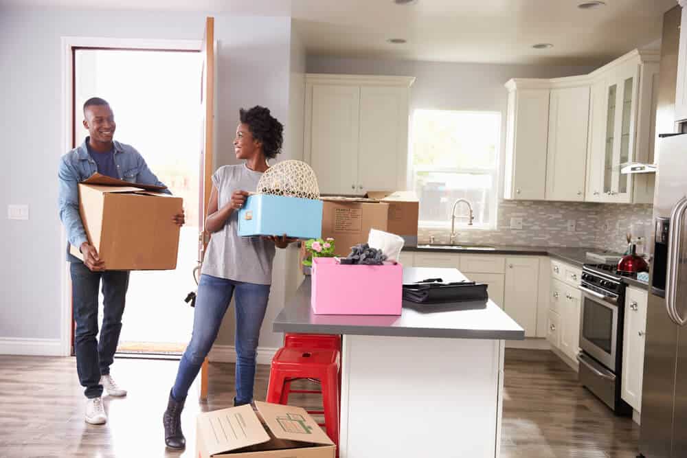 young happy couple carrying boxes into new rented apartment