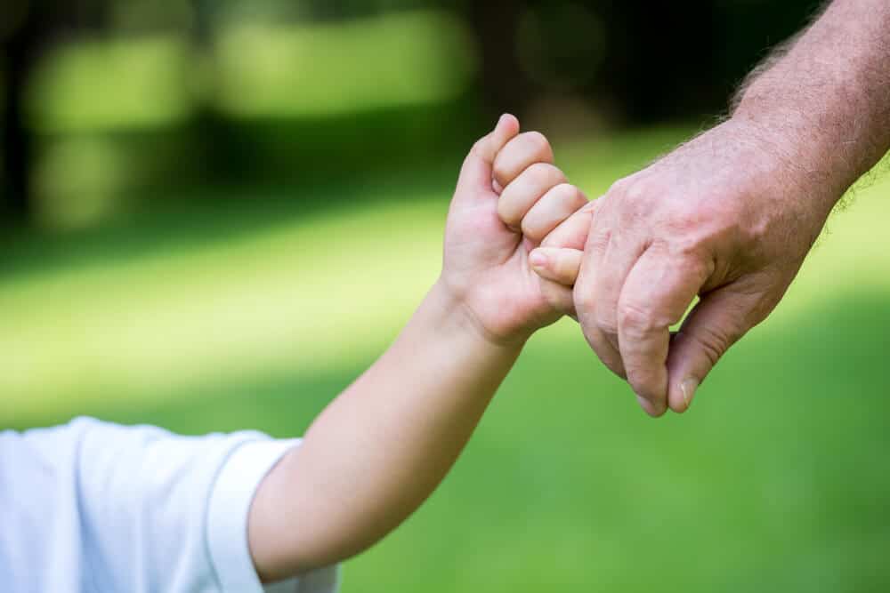 father holding pinkys with child