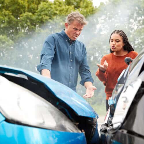 two cars in accident with drivers standing by arguing