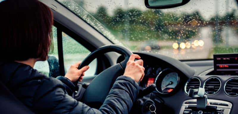 woman gripping steering wheel driving in rainy weather