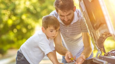 Man and child check the fluids of a car