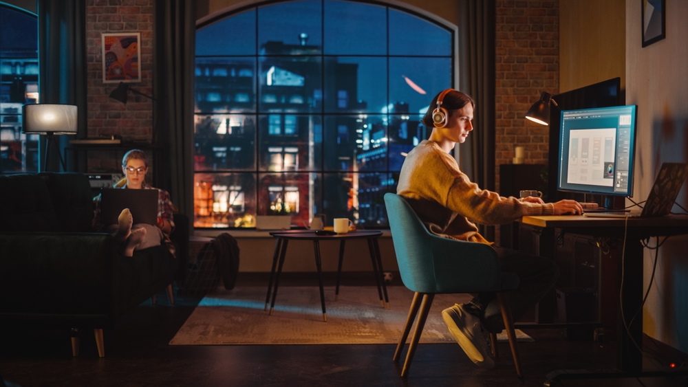 Apartment dwellers work in their loft at night on computers