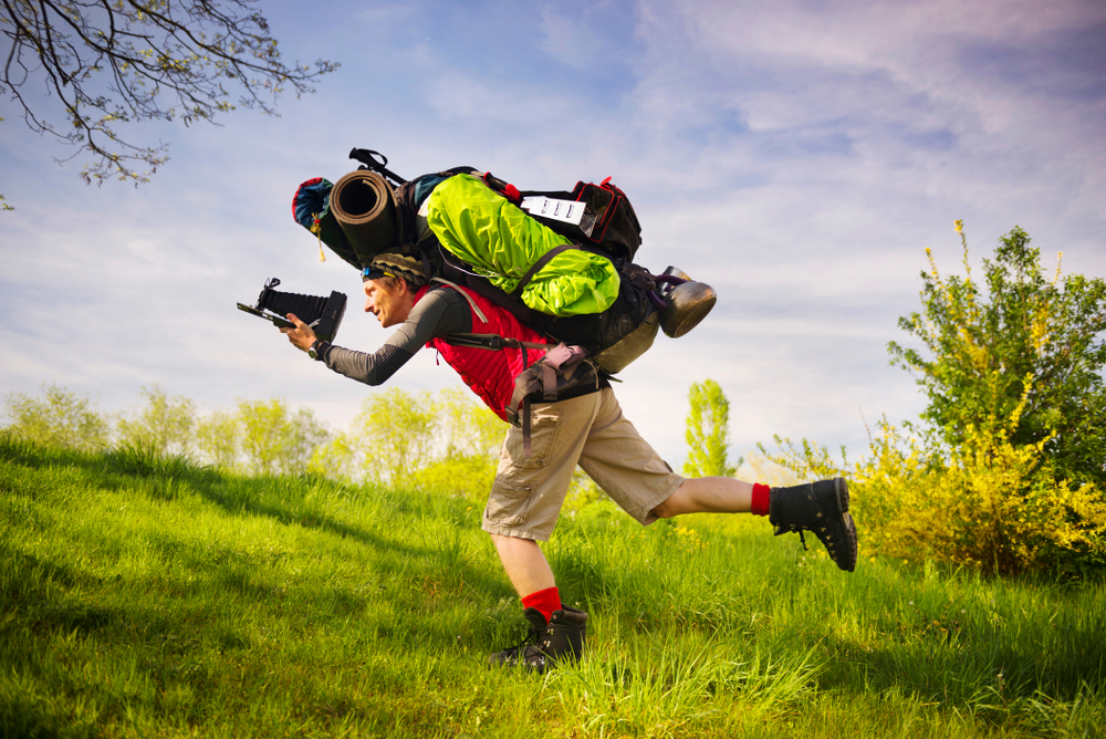 Man overloaded with camping and hiking gear.