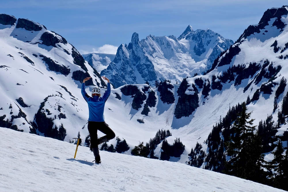 Woman in Yoga Pose Meditating and Enjoying Snow Covered Mountain View. Ruth Mountain, North Cascades National Park, Seattle, Washington State.