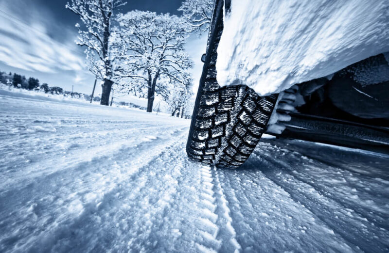 Close up of tire driving on snowy winter road.