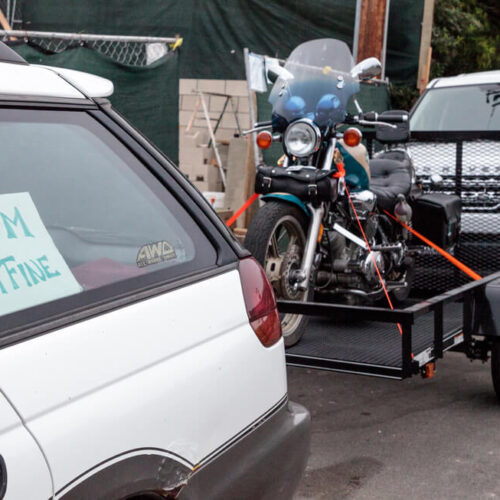 White vehicle hauling a trailer with a motorcycle on it - cheap car insurance in Washington.