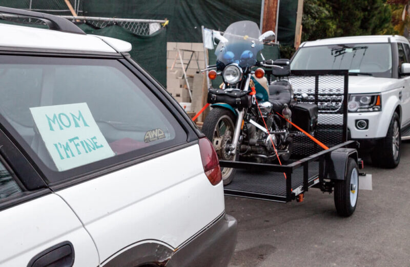 White vehicle hauling a trailer with a motorcycle on it - cheap car insurance in Washington.