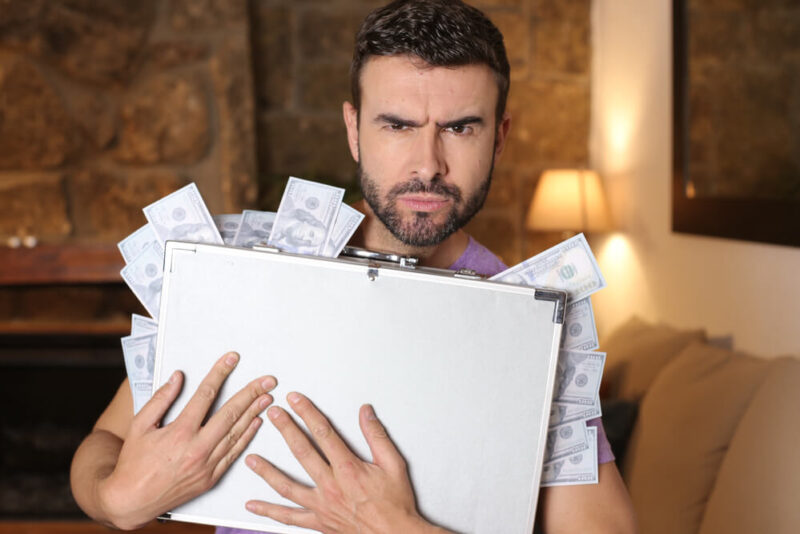 Hispanic man clutches his breifcase with money coming out after saving on bundling car insurance and home insurance.