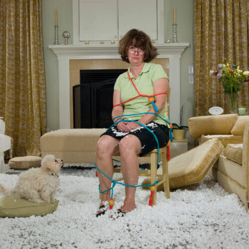 Woman tied up in her living room funny photo implying that her dog ruined her furniture and tied her up.