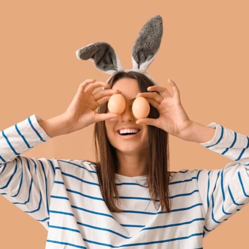 Silly young woman holding up eggs to her eyes with bunny ears.