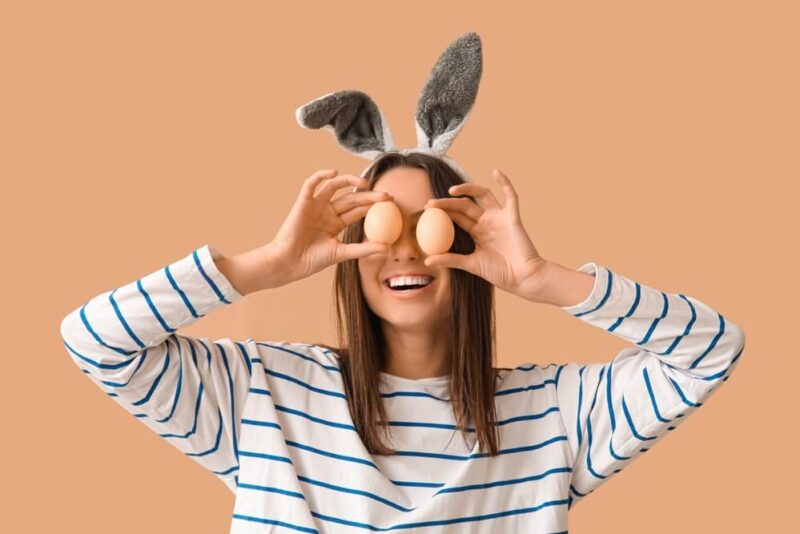 Silly young woman holding up eggs to her eyes with bunny ears.