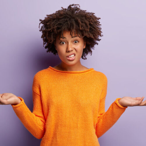 Confused woman in orange shirt with hands in air and puzzled expression on her face - cheap insurance in Washington State.