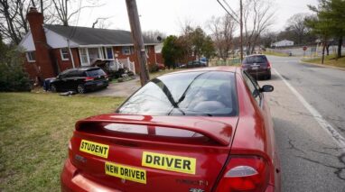 Student driver bumber sticker on a sports car parked on the street - cheapest car insurance in Washington.