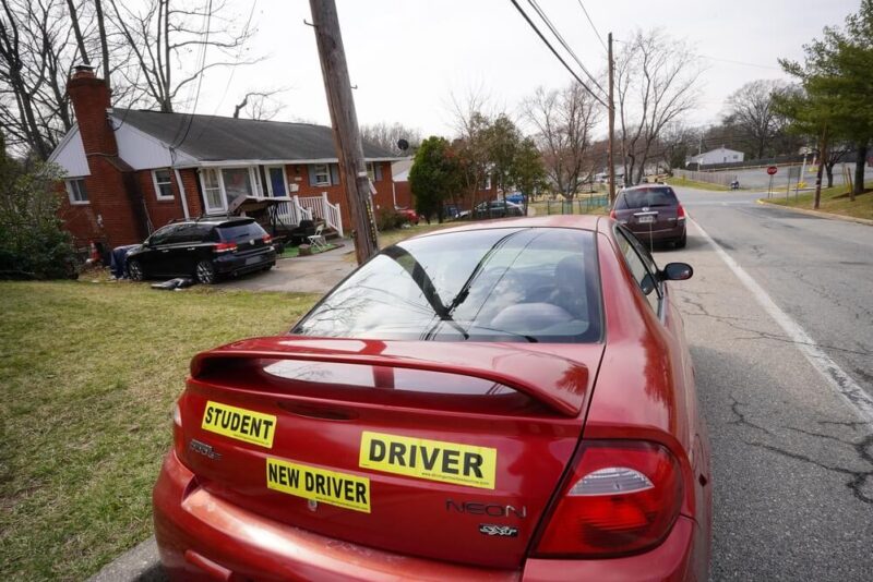 Student driver bumber sticker on a sports car parked on the street - cheapest car insurance in Washington.