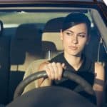 Beautiful happy woman driving her car in the evening